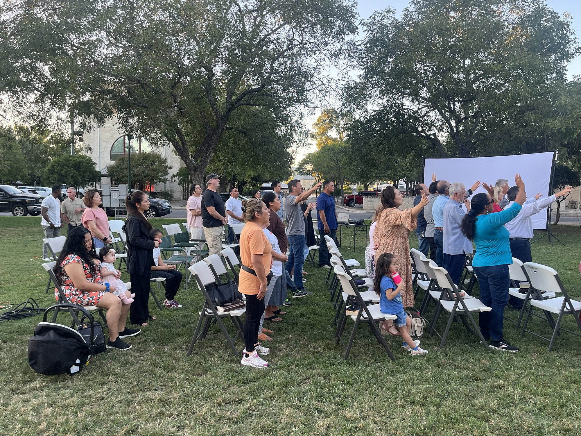 Attendees rise and raise hands in praise