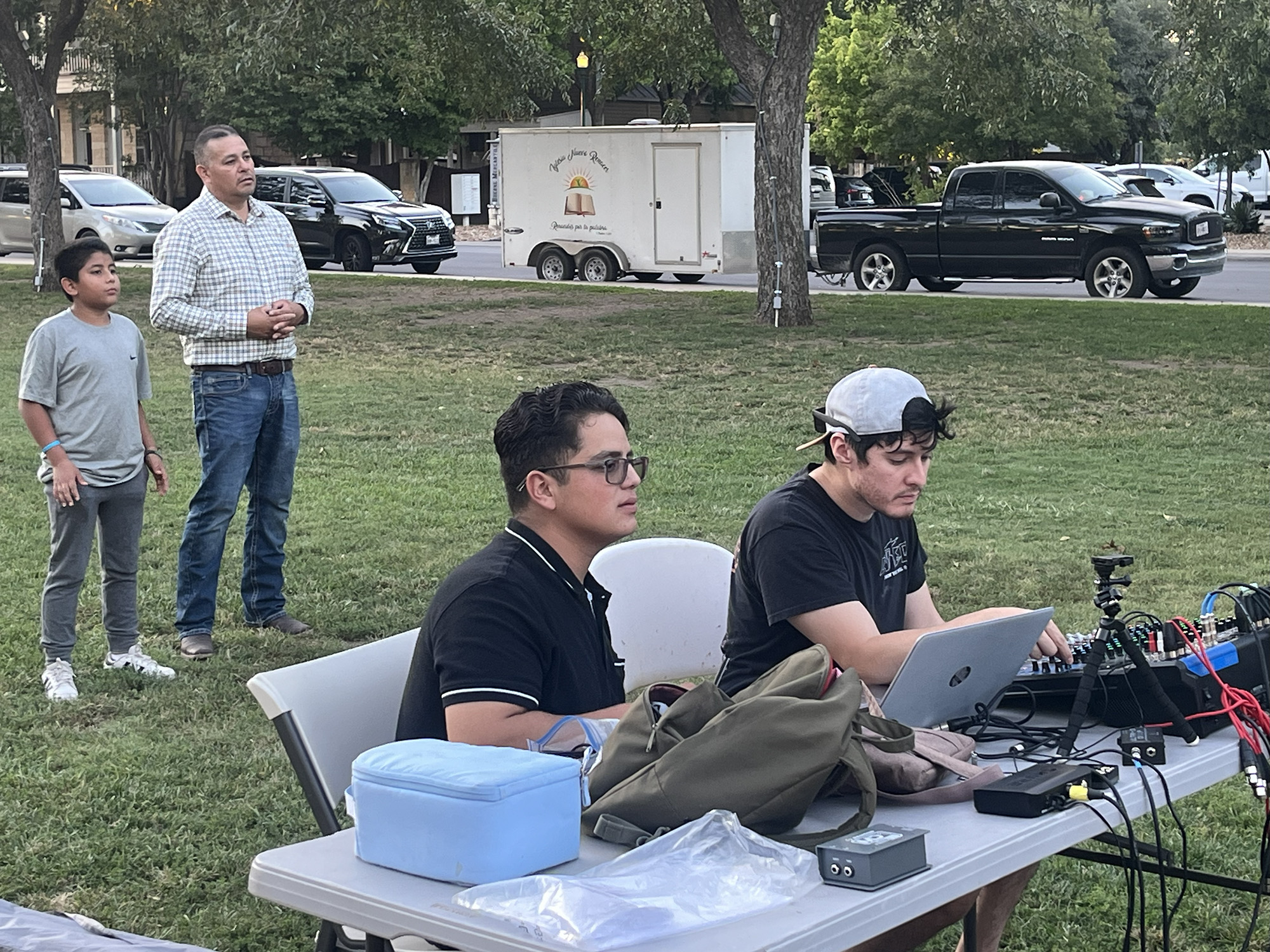 Matthew (Iglesia Shalom) and Fernando (Iglesia Nuevo Renacer) run sound; Ezekiel and son look on